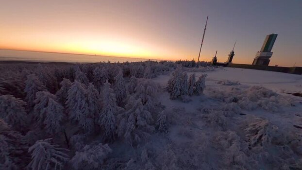 FPV aerial view of snowy Feldberg summit at sunset Germany.