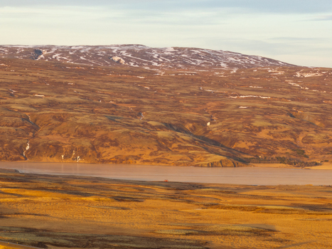 Aerial view of the rugged volcanic landscape with rolling hills patches of snow and a calm lake under the soft light of the golden hour in Reykjanesbaer Iceland. Aerial view of the rugged volcanic landscape with rolling hills patches of snow and a calm lake under the soft light of the golden hour in Reykjanesbaer Iceland.