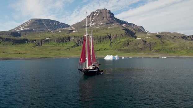 Aerial view of a sailboat with red sails in a bay Greenland. Aerial view of a sailboat with red sails in a bay Greenland.