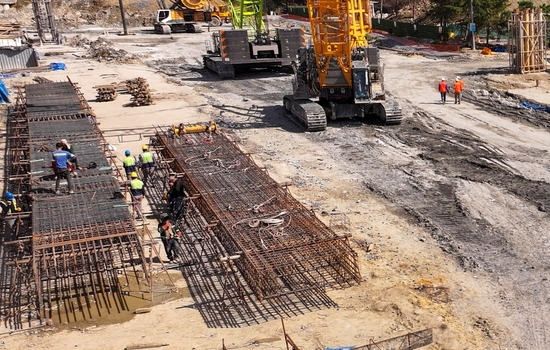Aerial view of construction workers assembling steel rebar cages near heavy machinery and cranes at a building site in Avcilar Istanbul Turkiye. Aerial view of construction workers assembling steel rebar cages near heavy machinery and cranes at a building site in Avcilar Istanbul Turkiye.