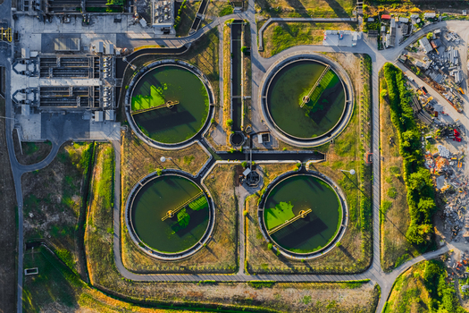 Aerial view of a water treatment plant featuring four large circular sedimentation tanks industrial infrastructure and surrounding green landscape in Rome Lazio Italy.
