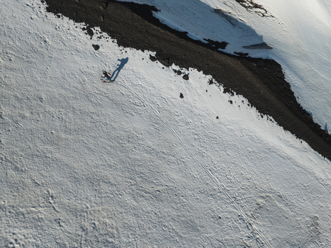 Aerial view of a skier descending the snowy southern slope of Mount Etna with dark volcanic rock and long shadows in Nicolosi Sicilia Italy. Aerial view of a skier descending the snowy southern slope of Mount Etna with dark volcanic rock and long shadows in Nicolosi Sicilia Italy.