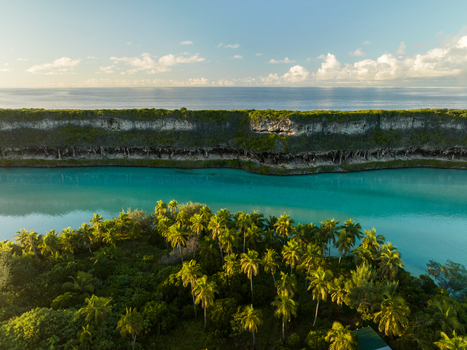 Aerial view of the vibrant turquoise waters meeting lush green vegetation and rugged cliffs under a serene sky Ouvéa Loyalty Islands Province New Caledonia. Aerial view of the vibrant turquoise waters meeting lush green vegetation and rugged cliffs under a serene sky Ouvéa Loyalty Islands Province New Caledonia.