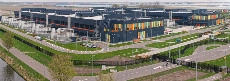 Aerial view of a large modern data center campus with industrial buildings back up energy infrastructure and surrounding green fields in Middenmeer Noord Holland Netherlands.