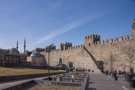 View of the historic Kayseri Castle with its ancient stone walls and battlements under a clear blue sky with people walking nearby in Kayseri Kayseri Turkiye. View of the historic Kayseri Castle with its ancient stone walls and battlements under a clear blue sky with people walking nearby in Kayseri Kayseri Turkiye.
