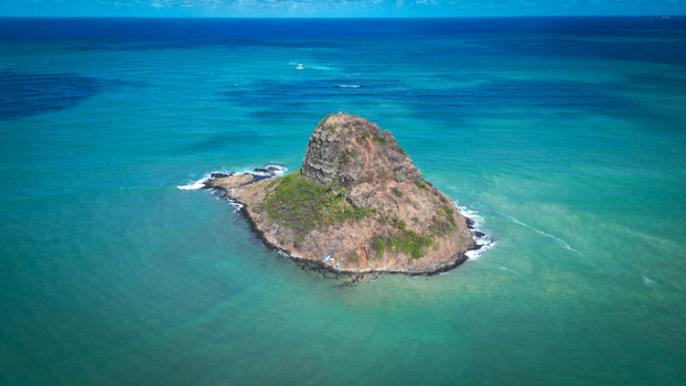 Aerial view of a rugged island rising from the turquoise ocean its rocky cliffs contrasting with the surrounding blue waters Kaneohe Hawaii United States. Aerial view of a rugged island rising from the turquoise ocean its rocky cliffs contrasting with the surrounding blue waters Kaneohe Hawaii United States.