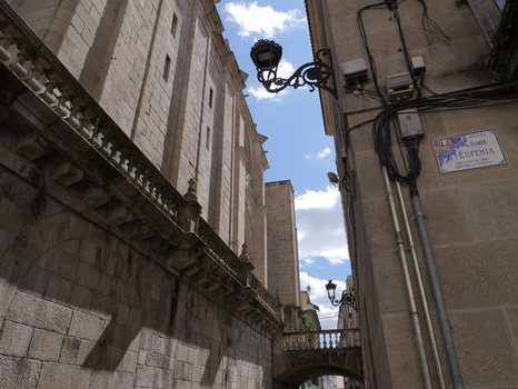 View of the historic stone architecture of the Church of Santa Eufemia in a narrow street with ornate street lamps and a blue sky in Ourense Province of Ourense Spain.
