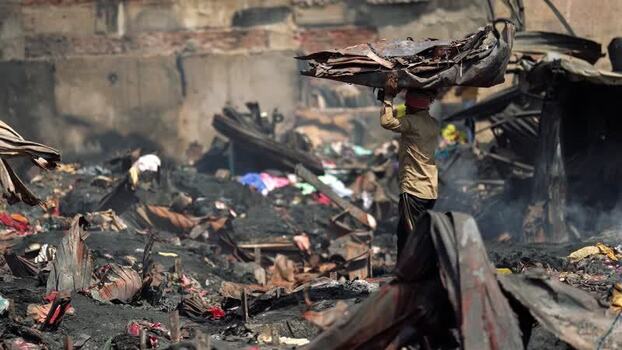 View of a man carrying debris in a burnt slum area Bangladesh. View of a man carrying debris in a burnt slum area Bangladesh.