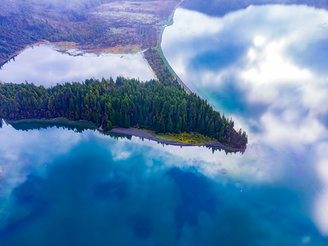 Aerial view of Lagoa do Fogo with its turquoise waters lush green forest peninsula and soft cloud reflections in Agua de Alto Azores Portugal. Aerial view of Lagoa do Fogo with its turquoise waters lush green forest peninsula and soft cloud reflections in Agua de Alto Azores Portugal.