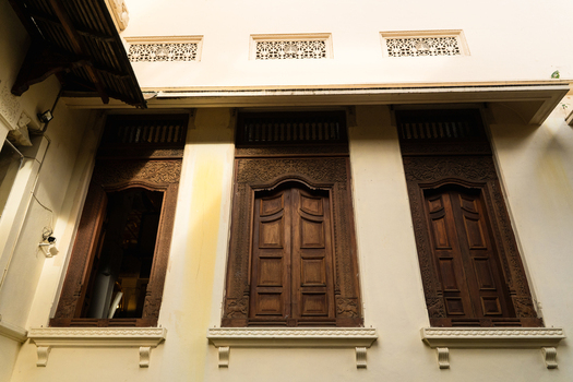 View of intricately carved wooden windows with traditional motifs on a historic building facade Kandy Central Province Sri Lanka. View of intricately carved wooden windows with traditional motifs on a historic building facade Kandy Central Province Sri Lanka.