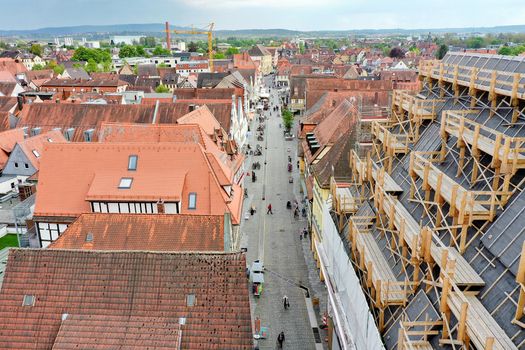 Aerial view of Rathaus Forchheim under renovation with scaffolding red tiled rooftops and people walking along the cobblestone street in Forchheim Bayern Germany.