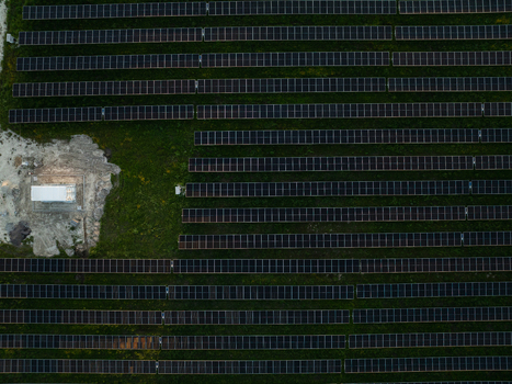 Aerial view of rows of solar panels in a large photovoltaic power plant on green grass with a small utility building in Augusta Sicily Italy. Aerial view of rows of solar panels in a large photovoltaic power plant on green grass with a small utility building in Augusta Sicily Italy.