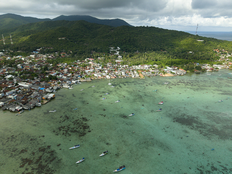 Aerial view of houses nestled along the coast where the deep green of the island contrasts with the turquoise sea Karimunjawa Central Java Indonesia. Aerial view of houses nestled along the coast where the deep green of the island contrasts with the turquoise sea Karimunjawa Central Java Indonesia.