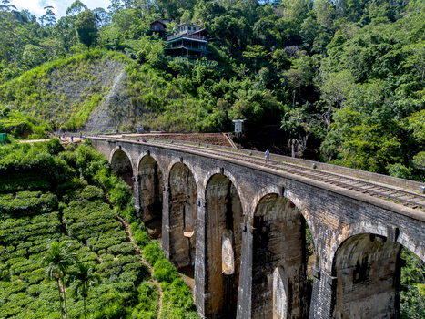 Aerial view of the historic Nine Arch Bridge surrounded by lush tea plantations and dense forest in Demodara Uva Province Sri Lanka. Aerial view of the historic Nine Arch Bridge surrounded by lush tea plantations and dense forest in Demodara Uva Province Sri Lanka.