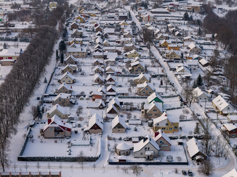 Aerial view of rows of residential houses with snow covered roofs and gardens in a quiet suburban neighborhood during winter in Lithuania. Aerial view of rows of residential houses with snow covered roofs and gardens in a quiet suburban neighborhood during winter in Lithuania.