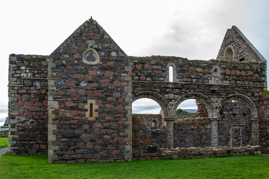 View of the Iona Nunnery featuring ancient stone walls Romanesque arches and lush green grass under an overcast sky in Baile Mor Scotland United Kingdom. View of the Iona Nunnery featuring ancient stone walls Romanesque arches and lush green grass under an overcast sky in Baile Mor Scotland United Kingdom.