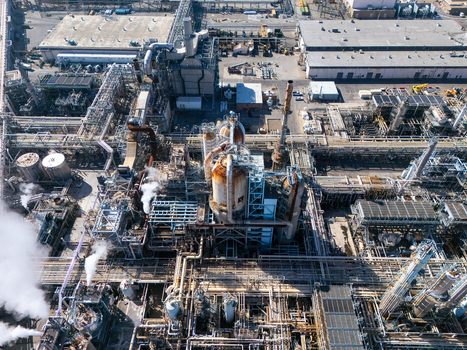 Aerial view of an industrial oil refinery complex with large storage tanks complex piping networks and smoke stacks in Carson California United States.
