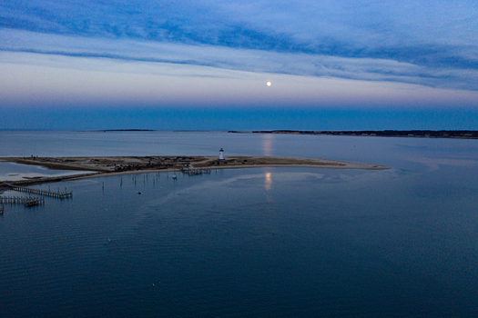 View of Martha s Vineyard featuring the Edgartown Harbor Light under a full moon reflecting on the calm sea at twilight Edgartown Massachusetts United States.