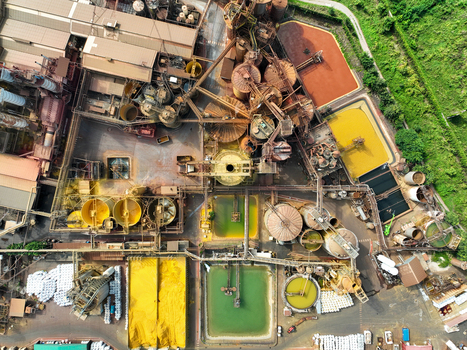 Aerial view of a large industrial plant with rusty silos complex piping systems and colorful sedimentation tanks surrounded by green vegetation Turin Piedmont Italy. Aerial view of a large industrial plant with rusty silos complex piping systems and colorful sedimentation tanks surrounded by green vegetation Turin Piedmont Italy.
