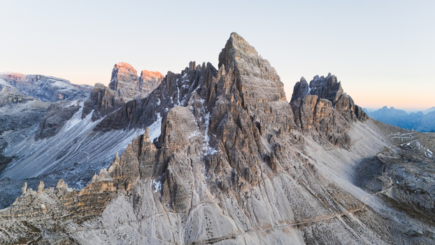Aerial view of the iconic Tre Cime di Lavaredo peaks with jagged limestone cliffs and rocky slopes under a clear sky in the Dolomites Auronzo di Cadore Veneto Italy. Aerial view of the iconic Tre Cime di Lavaredo peaks with jagged limestone cliffs and rocky slopes under a clear sky in the Dolomites Auronzo di Cadore Veneto Italy.