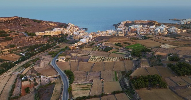 Aerial view of the coastal town of Marsalforn with its harbor surrounding agricultural fields and rocky coastline in Marsalforn Malta. Aerial view of the coastal town of Marsalforn with its harbor surrounding agricultural fields and rocky coastline in Marsalforn Malta.