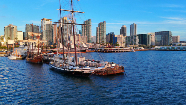 San Diego United States 01 April 2026 Aerial view of historic tall ships docked at the North Embarcadero with the modern San Diego skyline and blue harbor waters.