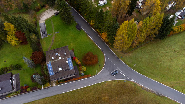 Aerial view of a road junction near a house with solar panels surrounded by autumn trees and green fields in Auronzo di Cadore Veneto Italy. Aerial view of a road junction near a house with solar panels surrounded by autumn trees and green fields in Auronzo di Cadore Veneto Italy.