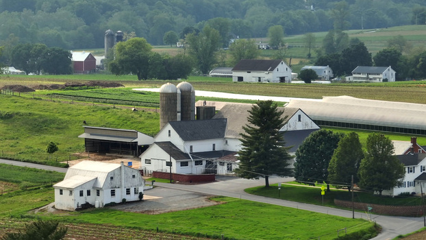 Aerial view of a farm with white farmhouses silos and barns surrounded by lush green fields in the rural landscape of Leola Pennsylvania United States.