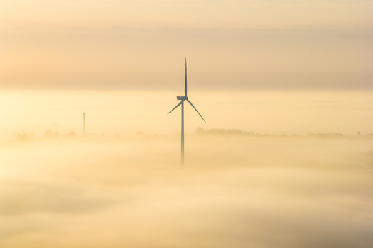 Aerial view of a wind turbine rising above a thick layer of morning fog in Poland. Aerial view of a wind turbine rising above a thick layer of morning fog in Poland.