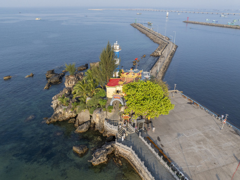 Aerial view of Dinh Cau Temple and its lighthouse perched on a rocky outcrop next to a long stone pier and the calm blue sea in Phu Quoc An Giang Vietnam. Aerial view of Dinh Cau Temple and its lighthouse perched on a rocky outcrop next to a long stone pier and the calm blue sea in Phu Quoc An Giang Vietnam.