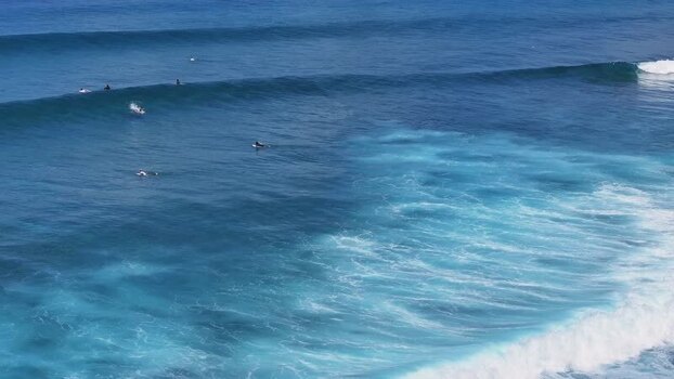 Aerial view of surfers riding waves in the Maldives.