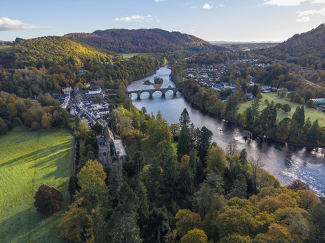 Aerial view of Dunkeld Cathedral and the stone bridge spanning the River Tay amidst vibrant autumn foliage and rolling hills Dunkeld Scotland United Kingdom. Aerial view of Dunkeld Cathedral and the stone bridge spanning the River Tay amidst vibrant autumn foliage and rolling hills Dunkeld Scotland United Kingdom.
