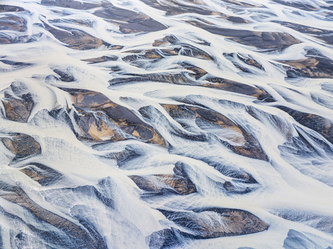 Aerial view of a complex braided river system with winding glacial channels and dark volcanic sediment patterns in Iceland. Aerial view of a complex braided river system with winding glacial channels and dark volcanic sediment patterns in Iceland.