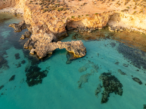 Aerial view of the Blue Lagoon s turquoise waters meeting the rugged cliffs a sun kissed paradise revealing the vibrant marine life beneath the surface Blue lagoon Comino Malta. Aerial view of the Blue Lagoon s turquoise waters meeting the rugged cliffs a sun kissed paradise revealing the vibrant marine life beneath the surface Blue lagoon Comino Malta.