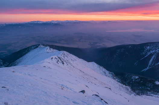 View of the snow covered peak of Baranec in the Western Tatras during a vibrant sunset with purple and orange skies over the mountain range in Jamnik Zilina Region Slovakia. View of the snow covered peak of Baranec in the Western Tatras during a vibrant sunset with purple and orange skies over the mountain range in Jamnik Zilina Region Slovakia.