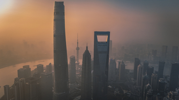 Aerial view of Lujiazui skyline featuring the Shanghai Tower and Shanghai World Financial Center during a hazy golden hour in Shanghai Shanghai China.