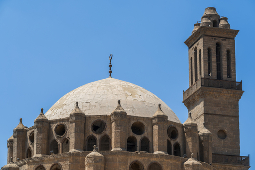 View of the historic Abu Dahab Mosque featuring its weathered stone dome and square minaret under a clear blue sky in El Darb El Ahmar Cairo Governorate Egypt. View of the historic Abu Dahab Mosque featuring its weathered stone dome and square minaret under a clear blue sky in El Darb El Ahmar Cairo Governorate Egypt.