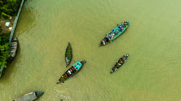 Aerial view of Baish Mowza Sarak Bazar with wooden boats carrying people and goods navigating the river in Nabinagar Chittagong Division Bangladesh. Aerial view of Baish Mowza Sarak Bazar with wooden boats carrying people and goods navigating the river in Nabinagar Chittagong Division Bangladesh.