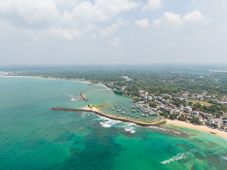 Aerial view of the harbor filled with fishing boats protected by a stone breakwater along the tropical coastline Hikkaduwa Southern Province Sri Lanka. Aerial view of the harbor filled with fishing boats protected by a stone breakwater along the tropical coastline Hikkaduwa Southern Province Sri Lanka.