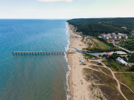 Aerial view of the long sandy beach a wooden pier extending into the Black Sea and the lush forest bordering the coastline in Shkorpilovtsi Varna Bulgaria. Aerial view of the long sandy beach a wooden pier extending into the Black Sea and the lush forest bordering the coastline in Shkorpilovtsi Varna Bulgaria.