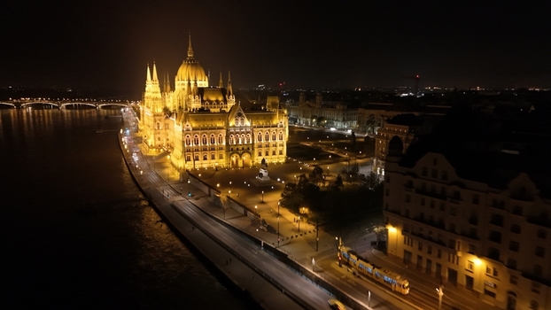 Aerial view of the illuminated Hungarian Parliament Building at night situated along the Danube River in Budapest Hungary.