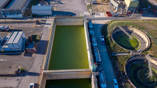 Aerial view of the Water Treatment Centre Camberley featuring large rectangular and circular sedimentation tanks with green water and industrial vehicles in Camberley England United Kingdom. Aerial view of the Water Treatment Centre Camberley featuring large rectangular and circular sedimentation tanks with green water and industrial vehicles in Camberley England United Kingdom.