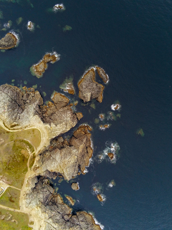Aerial view of the rugged rocky coastline of Pointe des Poulains with crashing waves and deep blue sea in Sauzon Bretagne France. Aerial view of the rugged rocky coastline of Pointe des Poulains with crashing waves and deep blue sea in Sauzon Bretagne France.