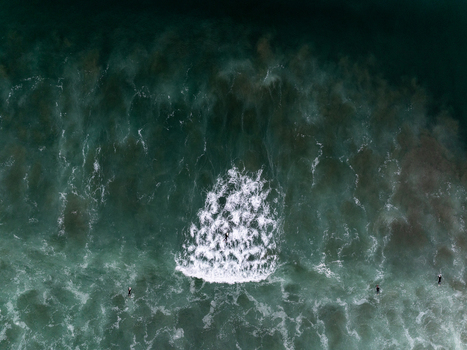 Aerial view of surfers waiting for waves in the deep blue ocean with white foam patterns in Whangamata Coromandel New Zealand. Aerial view of surfers waiting for waves in the deep blue ocean with white foam patterns in Whangamata Coromandel New Zealand.