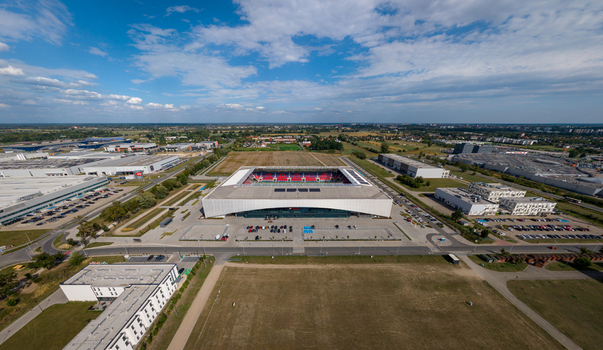 Opole Poland 09 September 2026 Aerial view of Itaka Arena stadium surrounded by parking lots industrial buildings and green fields under a blue sky with scattered clouds. Opole Poland 09 September 2026 Aerial view of Itaka Arena stadium surrounded by parking lots industrial buildings and green fields under a blue sky with scattered clouds.