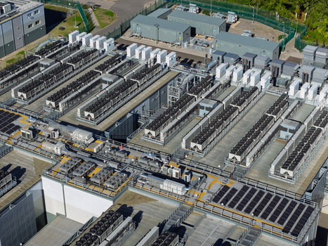 Aerial view of a large data center facility featuring rows of cooling units industrial HVAC equipment and solar panels on the roof in the United Kingdom.