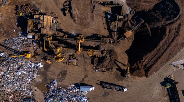 Aerial view of a scrap metal facility featuring heavy machinery conveyor belts and large piles of processed metal with excavators and trucks in Kalamazoo Michigan United States.