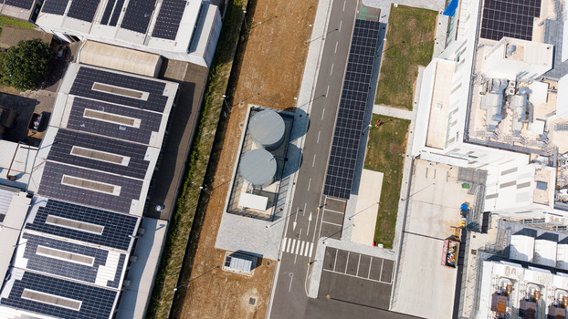 Aerial view of a modern data center campus with solar panels on rooftops large storage tanks and paved access roads in Melegnano Lombardy Italy.