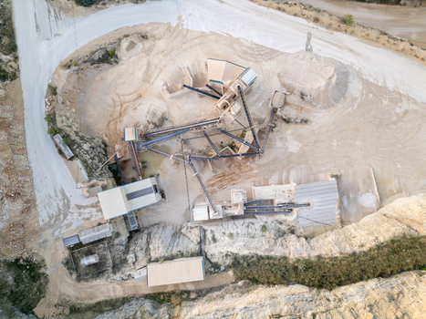 Aerial view of a stone quarry with industrial crushing machinery conveyor belts and piles of gravel in Teulada Valencian Community Spain.