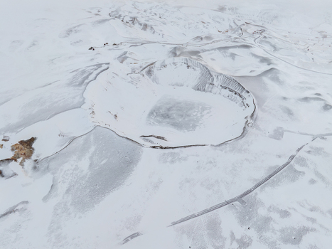 Aerial view of the snow covered Hverfjall volcanic crater near Myvatn featuring dramatic dark slopes and geothermal steam vents in the surrounding landscape in Thingeyjarsveit Iceland. Aerial view of the snow covered Hverfjall volcanic crater near Myvatn featuring dramatic dark slopes and geothermal steam vents in the surrounding landscape in Thingeyjarsveit Iceland.